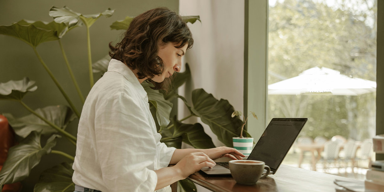 Woman in white working on a fundraising efficiency plan on her laptop