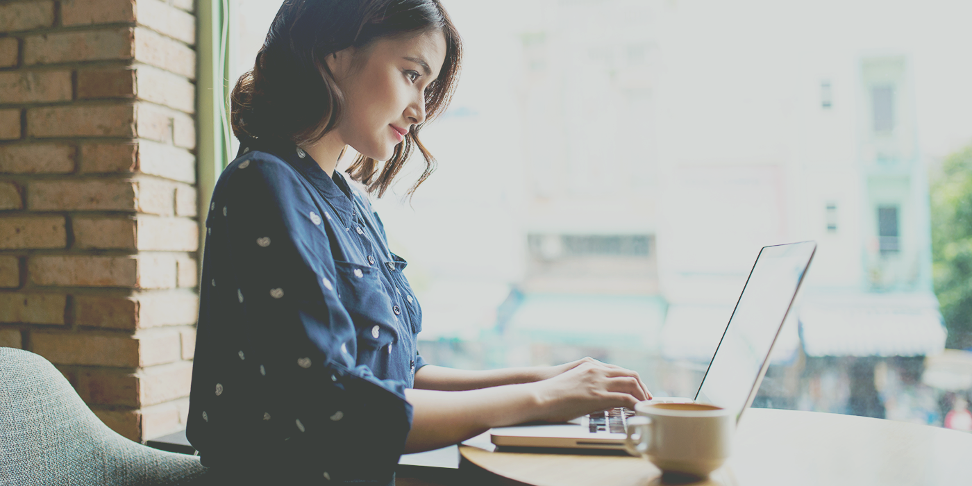woman in blue typing on laptop
