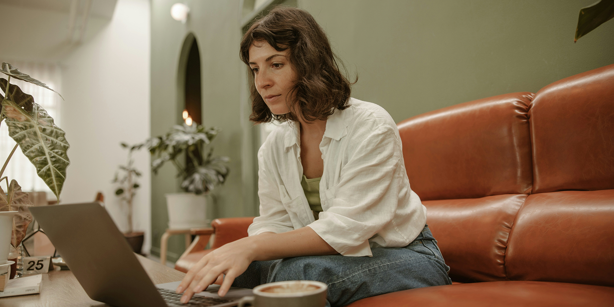 Woman sitting on couch researching GoFundMe Pro's types of fundraising campaigns