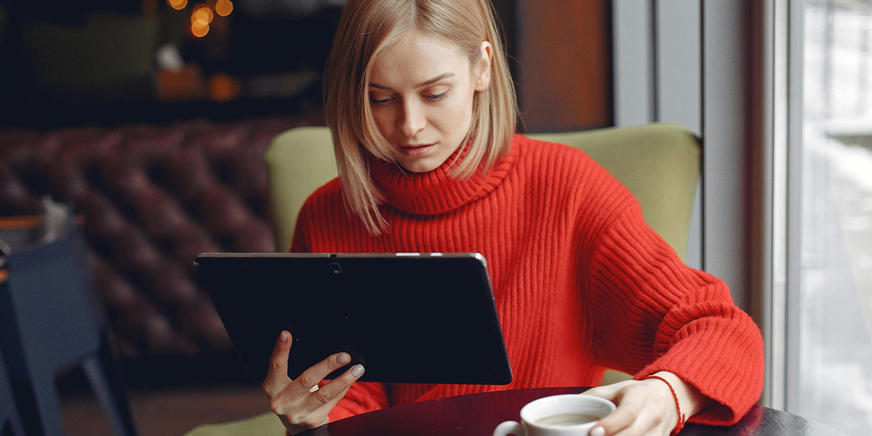 Woman in red sweater downloading fundraising email templates from her tablet