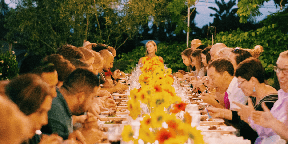 people sharing a meal at a dinner table with flowers