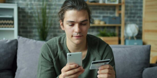 Person holding a credit card while looking at their phone