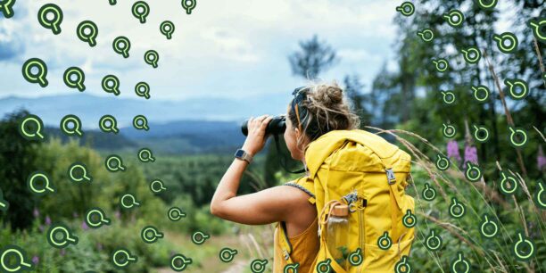 Woman looking through binoculars while on a hike